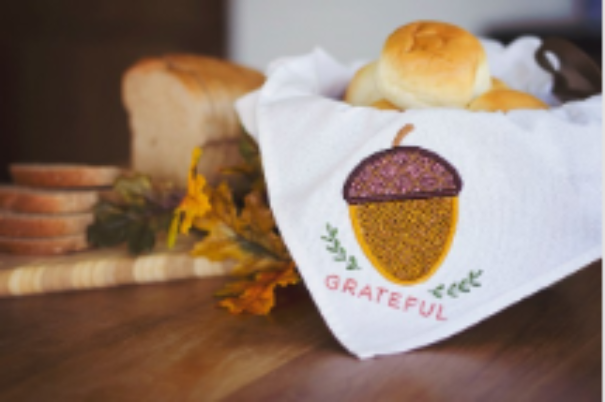 Bread with a decorative towel featuring an acorn design on a wooden surface.