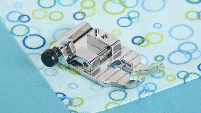 Metal sewing machine foot on a fabric with colorful circle pattern