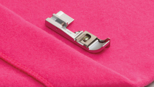 Sewing machine presser foot on a pink fabric background