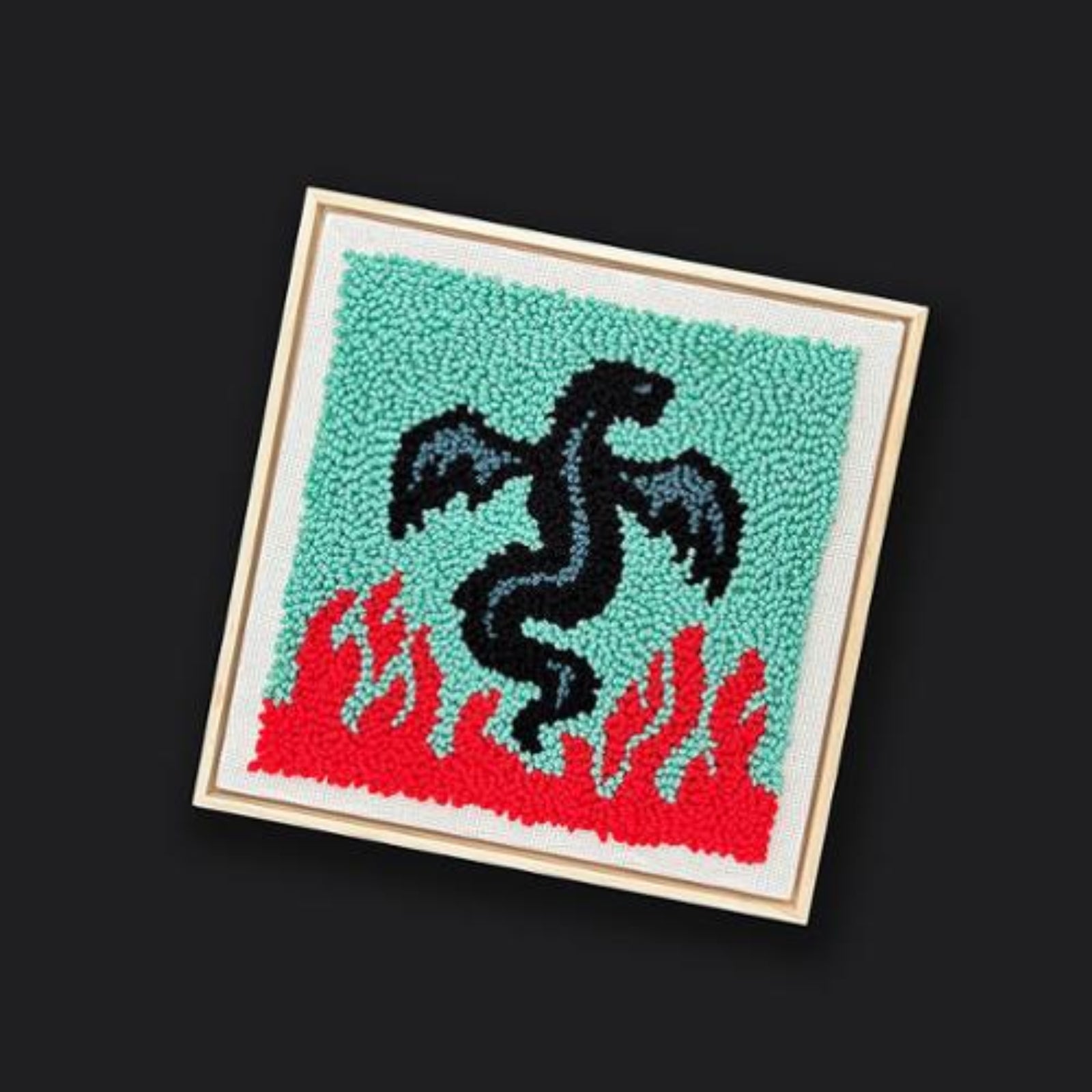 Embroidered patch with a black dragon design on a teal background with red flames, framed by a wooden border.