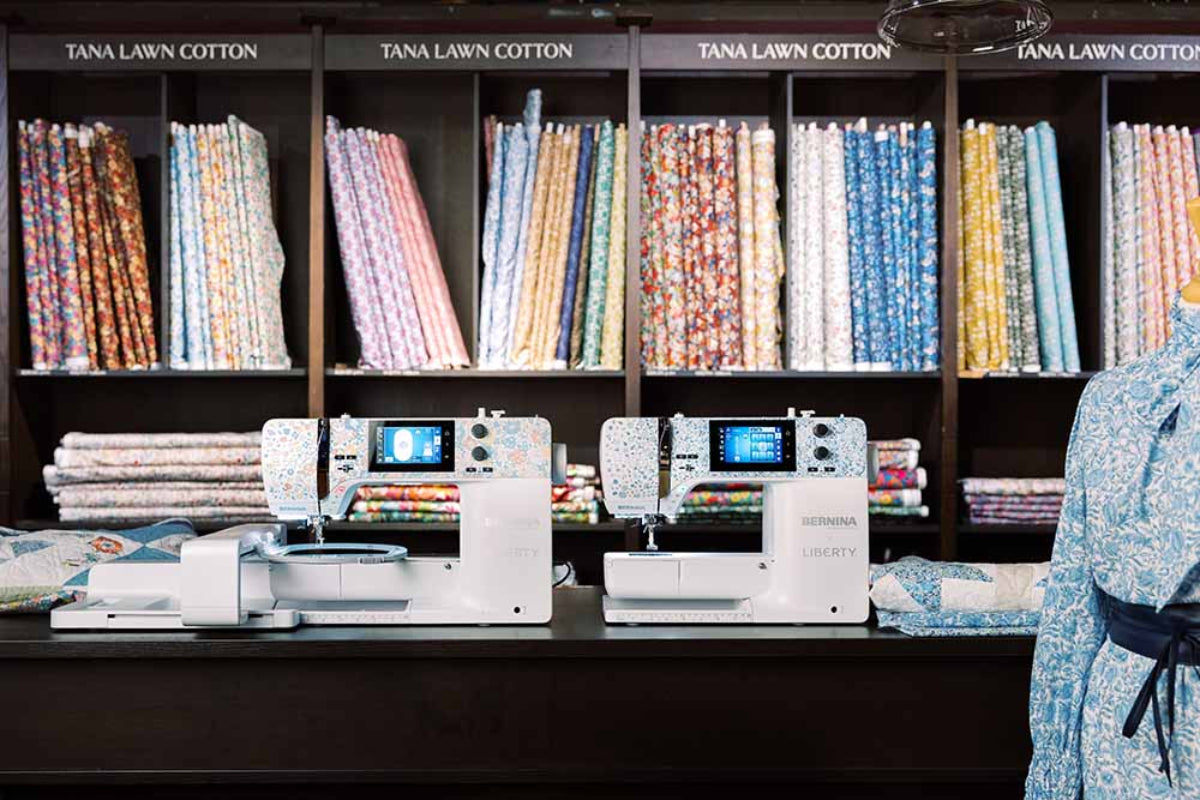 Sewing machines on a counter with fabric rolls in the background