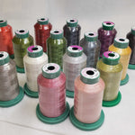 A collection of colorful spools of thread. The spools come in a variety of colors including red, green, purple, yellow, pink, and silver, each mounted on a green plastic base.
