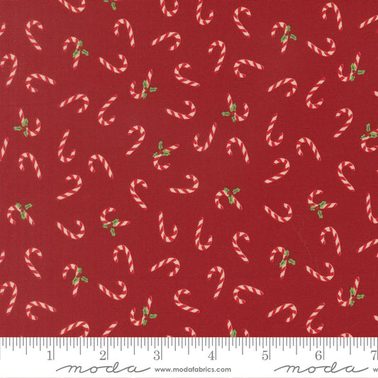 Pattern of candy canes and holly leaves on a red background with a ruler for scale
