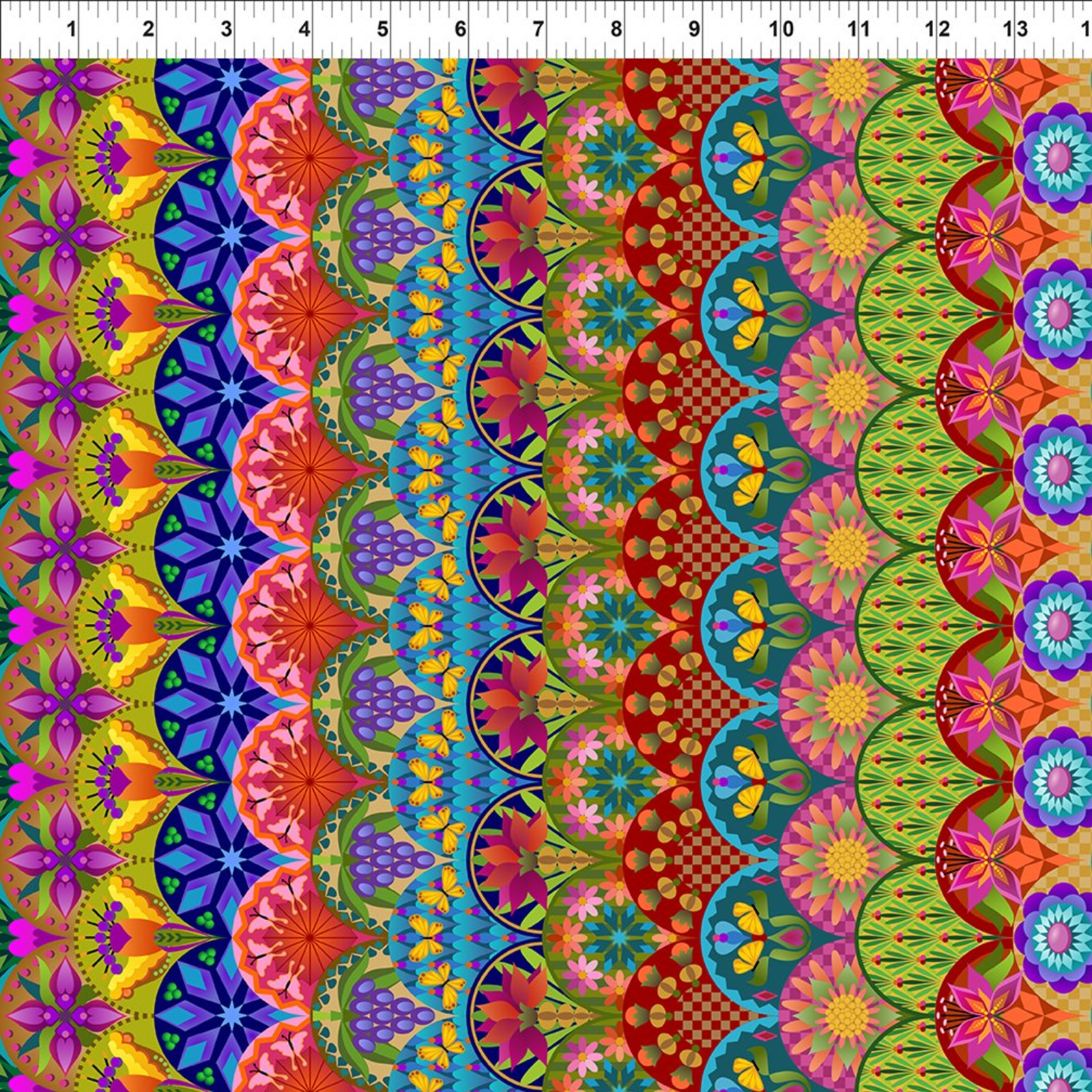 A close-up of a highly colorful patterned fabric with vertical bands of repeating floral and geometric motifs in pink, orange, red, yellow, green, blue, purple, and teal. A white ruler with black markings is visible along the top edge for scale.