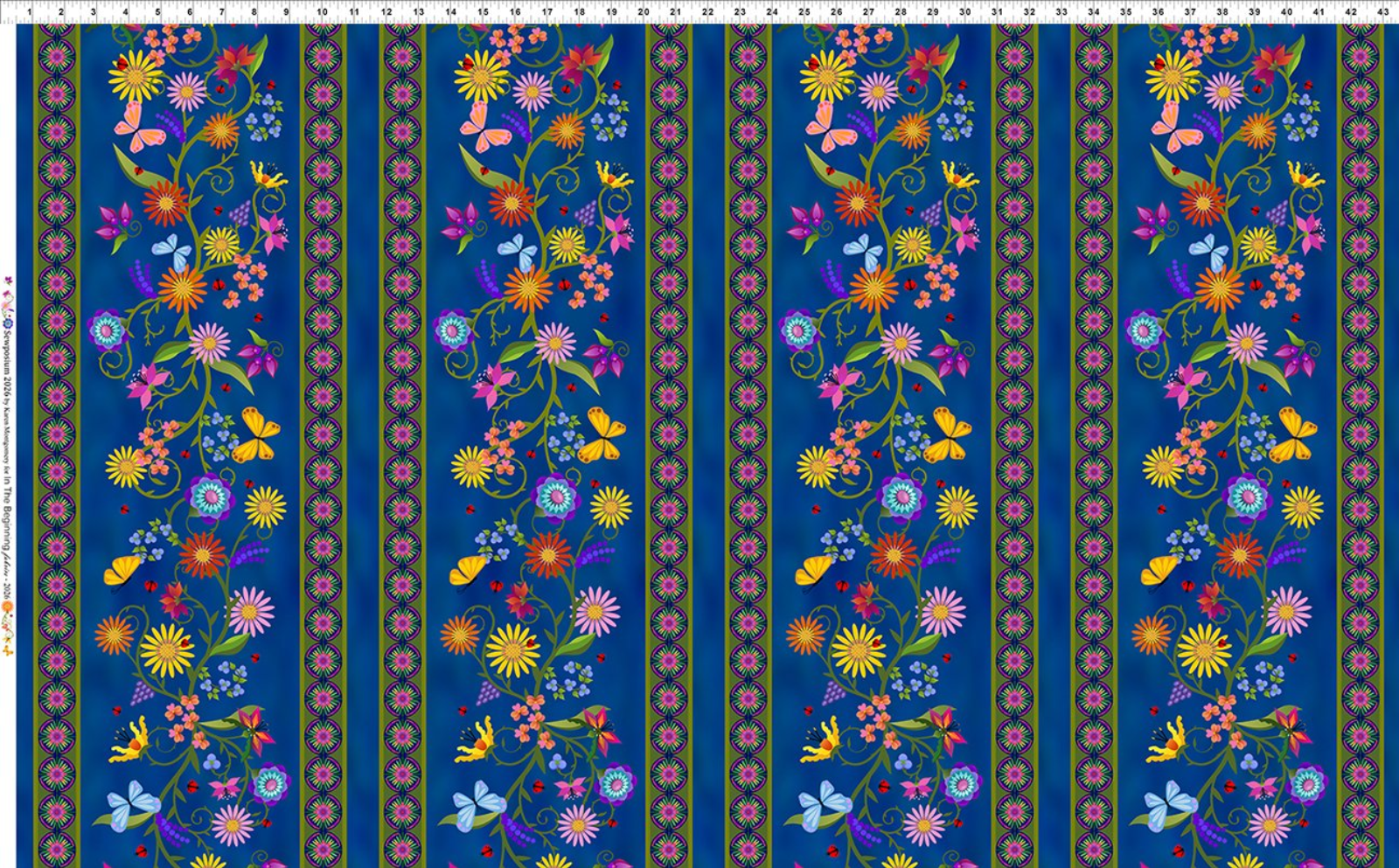 A patterned fabric with horizontal floral motifs on a deep blue background, featuring yellow, pink, purple, orange, and green flowers, butterflies, and ornamental borders. A ruler scale is visible along the top and left edge.