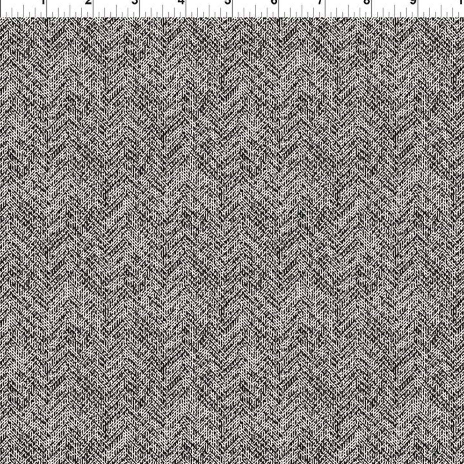 A close-up of a woven fabric with a black and white herringbone pattern, shown with a 12-inch ruler along the top edge for scale.