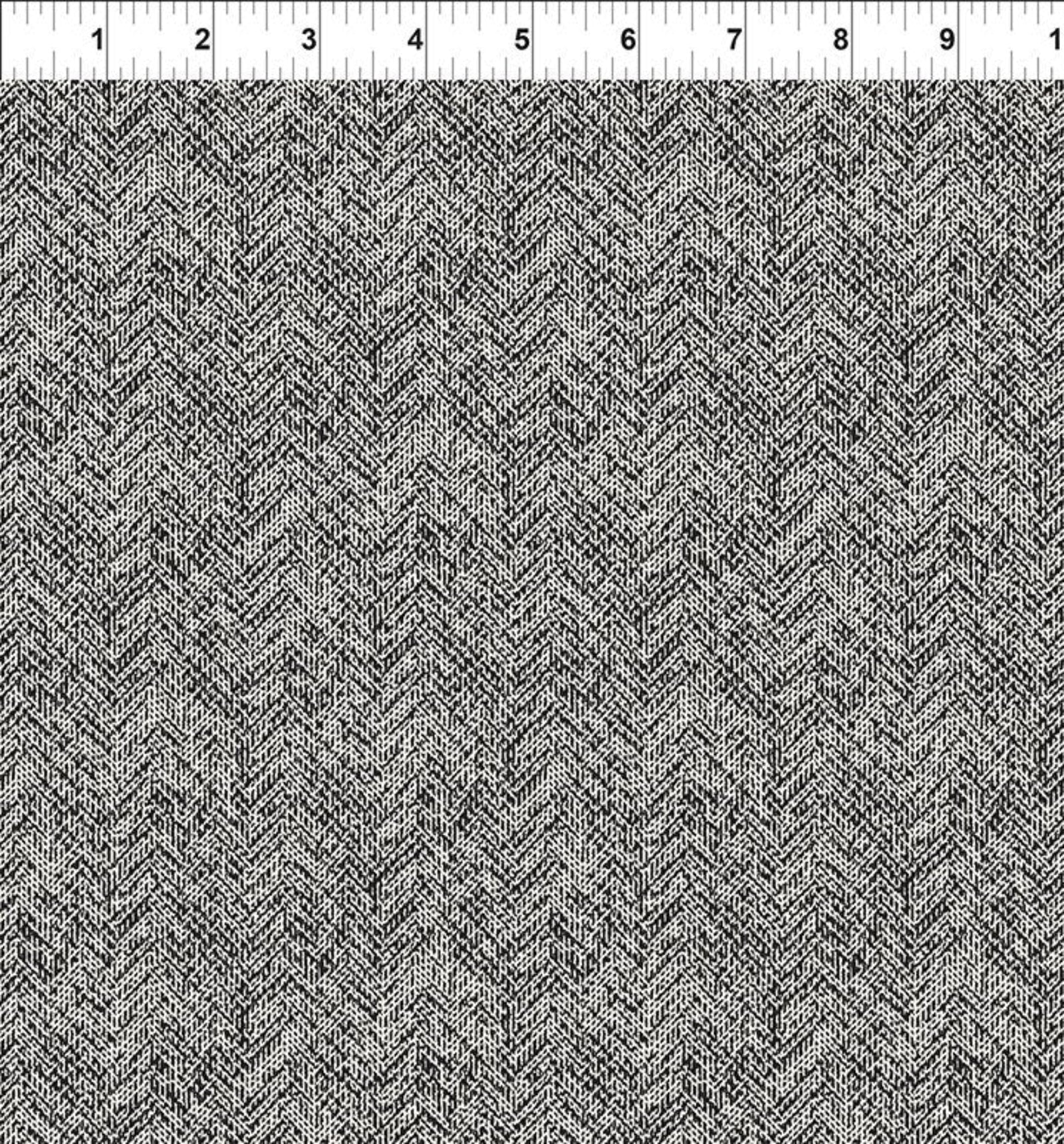 A close-up of a woven fabric with a black and white herringbone pattern, shown with a 12-inch ruler along the top edge for scale.