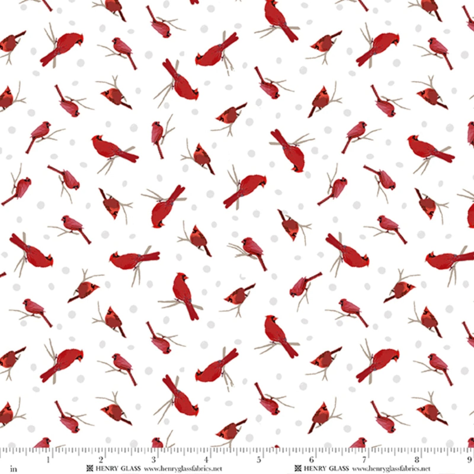 White fabric with a repeating pattern of red cardinal birds perched on branches, with small light gray polka dots and a ruler along the bottom edge showing scale.