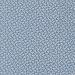 A close-up of a fabric featuring a repeating small leaf motif on a dusty blue background.