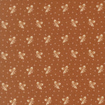 A close-up of a brown fabric or wallpaper pattern featuring a repeating motif of cream-colored bows, small diamond shapes, and tiny leaf-like accents.