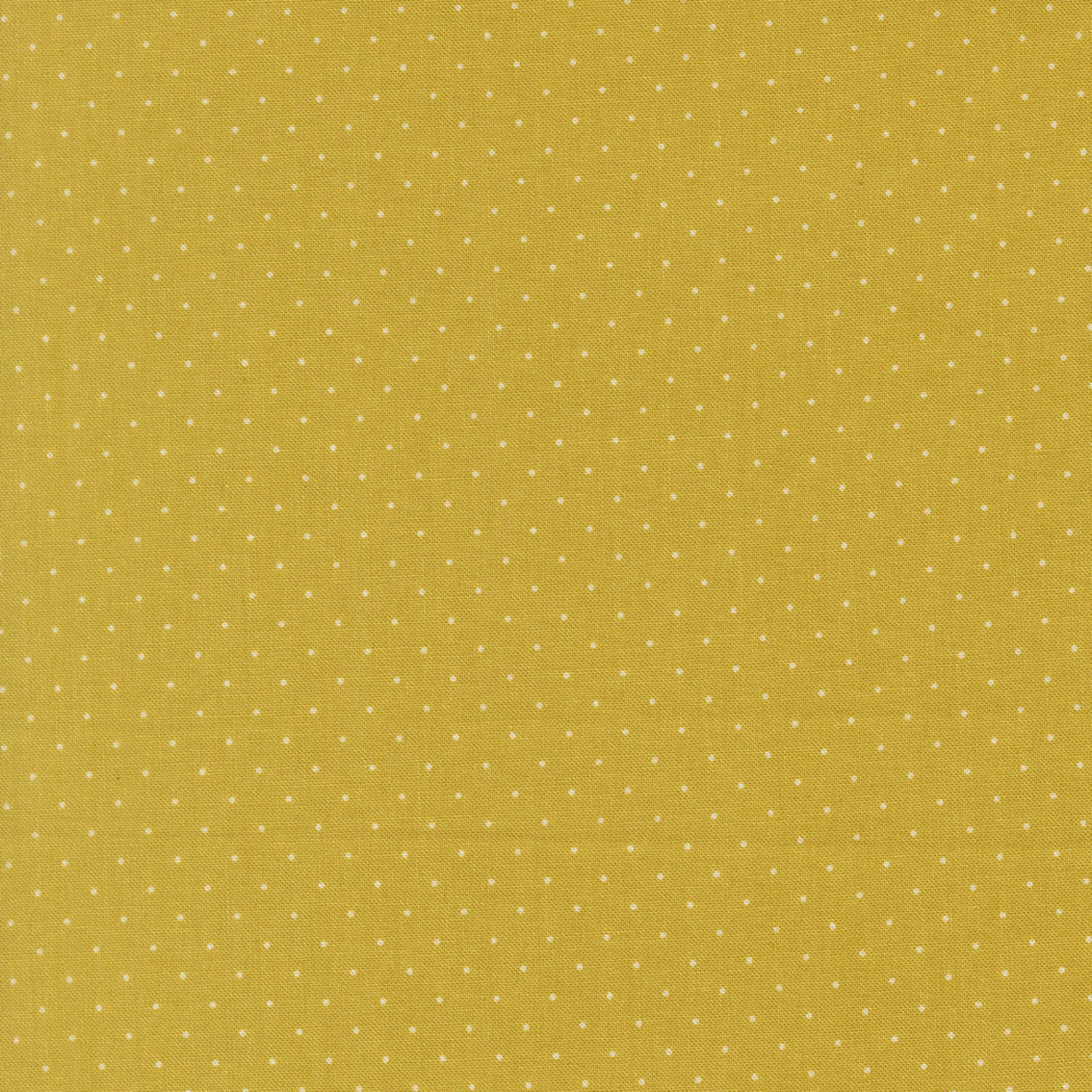 A close-up of a mustard yellow fabric with a repeating pattern of small white polka dots.