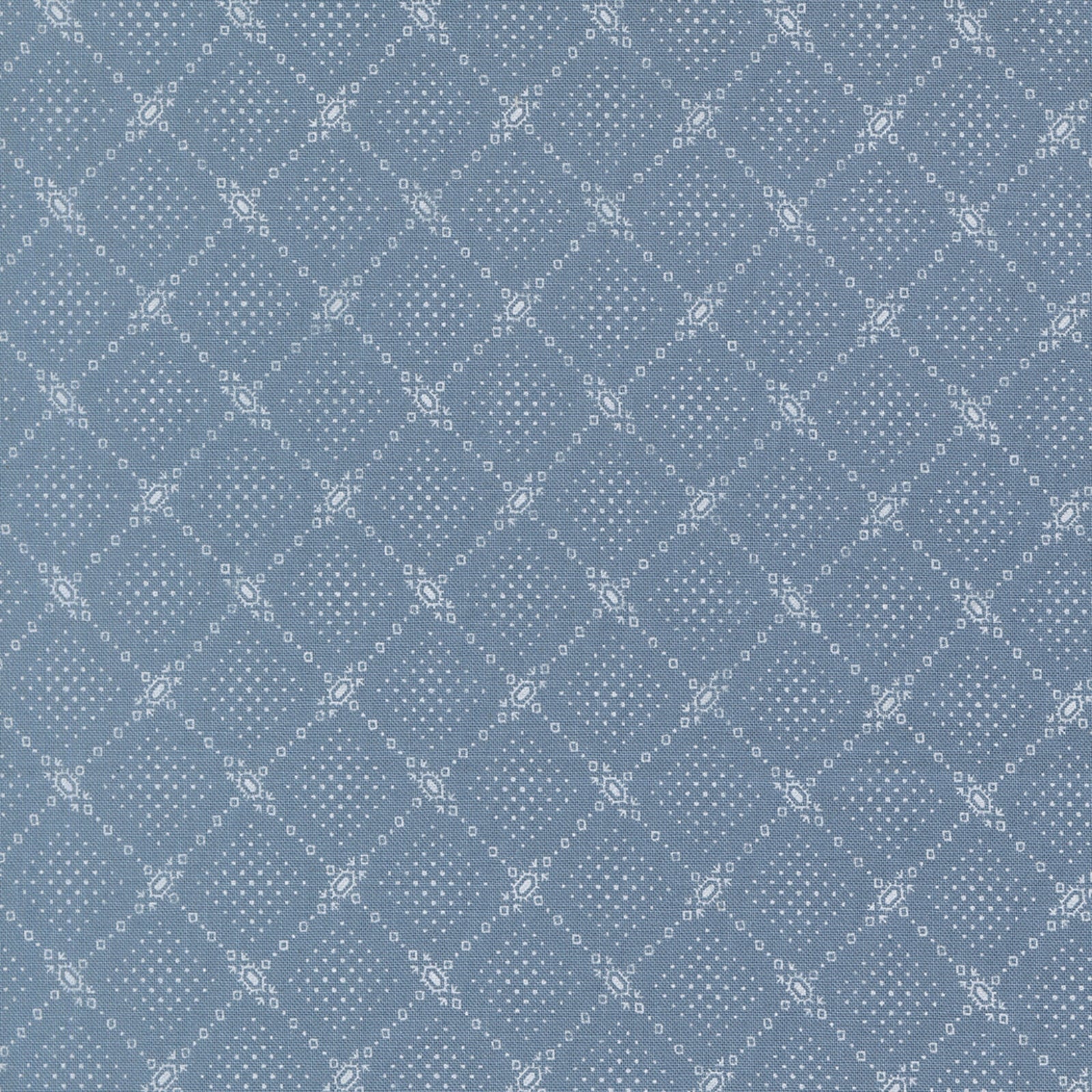 A close-up of a blue fabric featuring a repeating white geometric diamond lattice with small dots and decorative floral motifs.