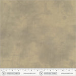 A close-up of a fabric swatch in a warm beige/taupe color with a subtle mottled texture, featuring a ruler at the bottom for scale and the Windham Fabrics logo.