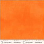 A close-up of bright orange fabric texture with a ruler along the bottom edge and Windham Fabrics branding printed across the lower band.