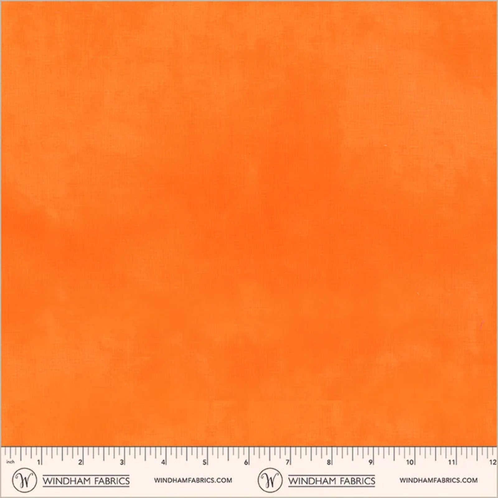 A close-up of bright orange fabric texture with a ruler along the bottom edge and Windham Fabrics branding printed across the lower band.