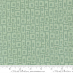 Patterned fabric with geometric shapes on a green background with a ruler for scale