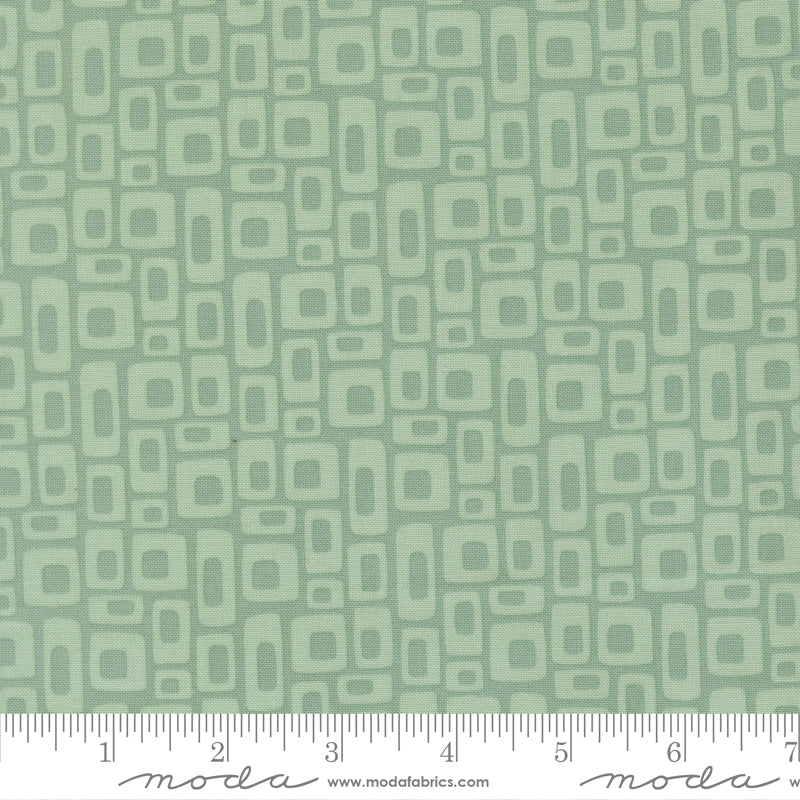Patterned fabric with geometric shapes on a green background with a ruler for scale