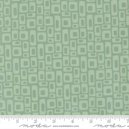 Patterned fabric with geometric shapes on a green background with a ruler for scale