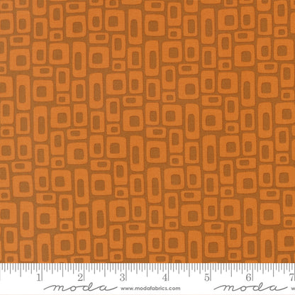 Patterned fabric with geometric shapes on a brown background, featuring a ruler at the bottom for scale.