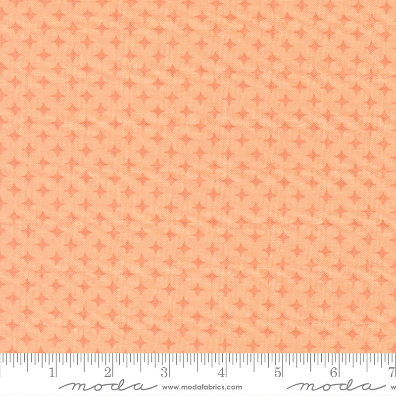 Patterned fabric with a small diamond design on a peach background, featuring ruler for scale