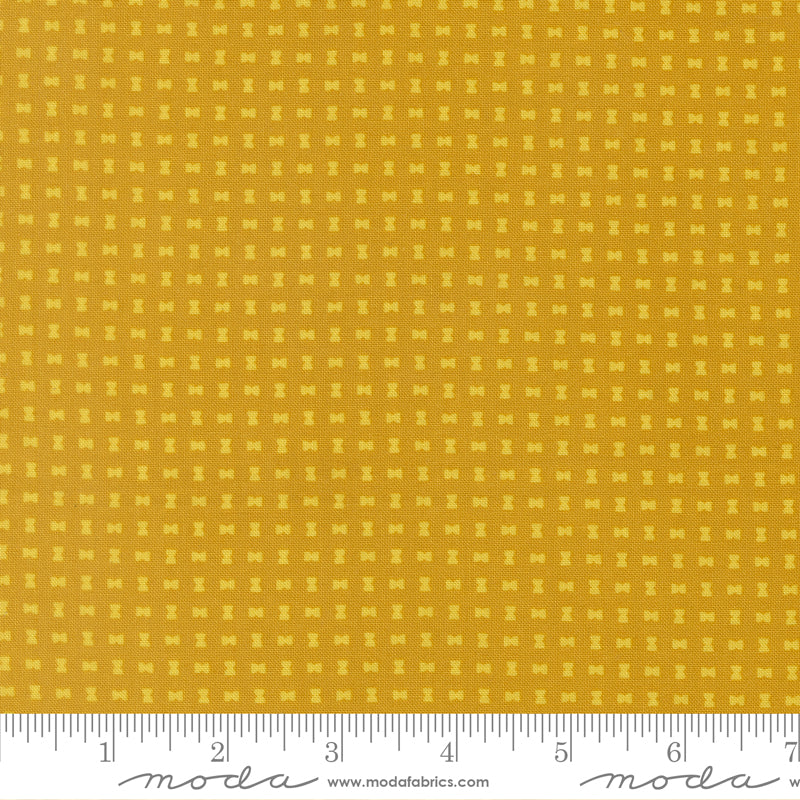 Yellow fabric with a small pattern and a ruler at the bottom for scale.