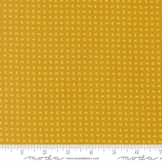 Yellow fabric with a small pattern and a ruler at the bottom for scale.