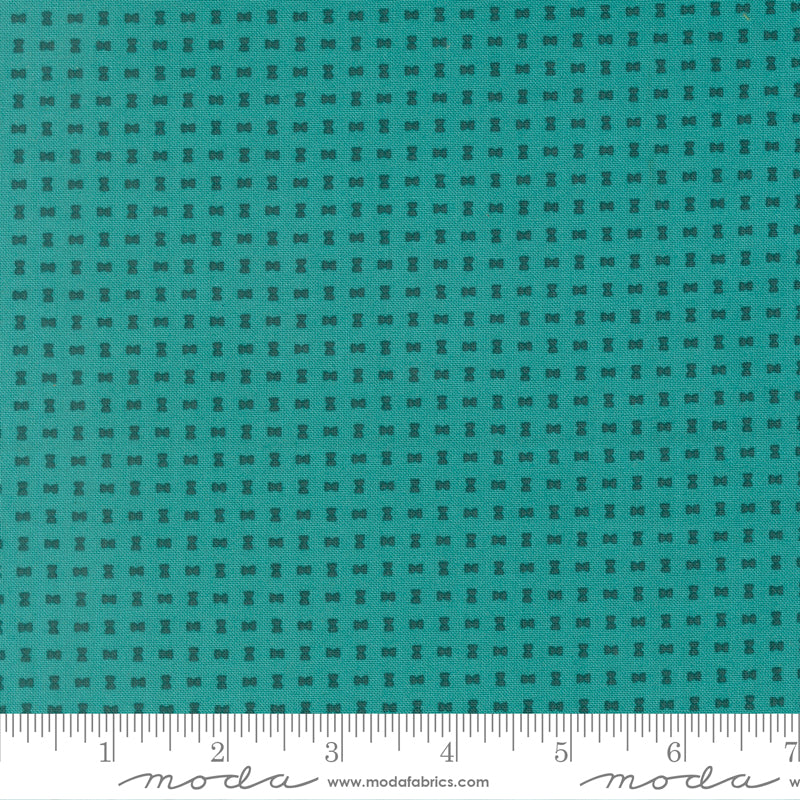 Teal fabric with a small checkered pattern and a ruler at the bottom for scale.