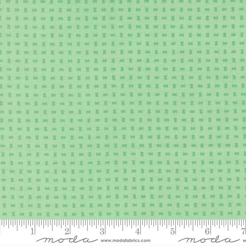 Green fabric pattern with a ruler for scale on a green background