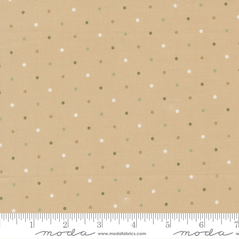 Fabric with small polka dots on a beige background, featuring a ruler at the bottom for scale.