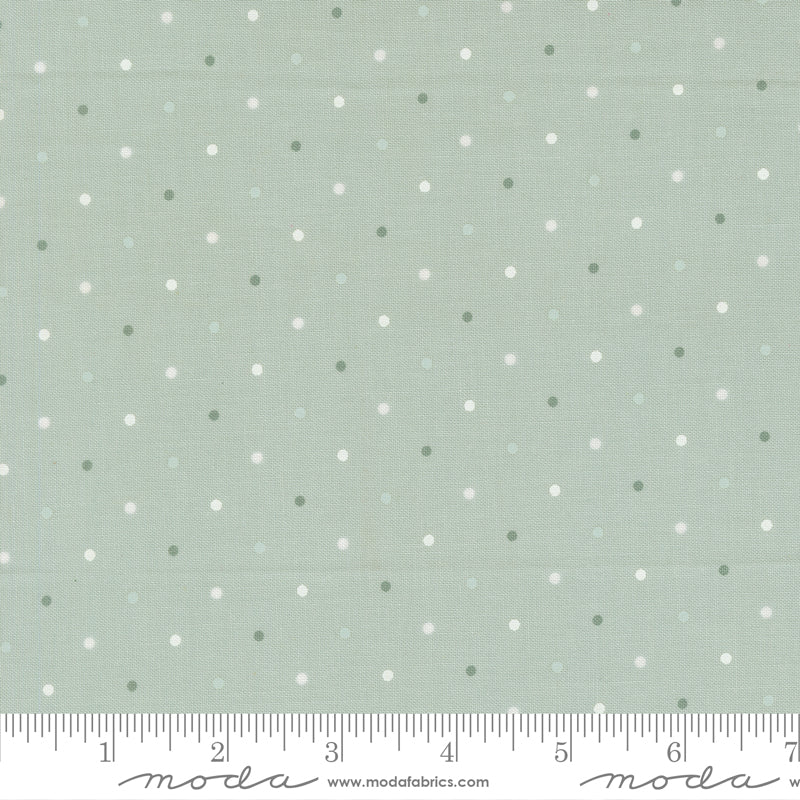Fabric swatch with small polka dots on a light gray background, featuring a ruler for scale