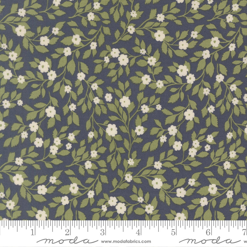 Floral pattern fabric with green leaves and white flowers on a blue background, featuring a ruler for scale.