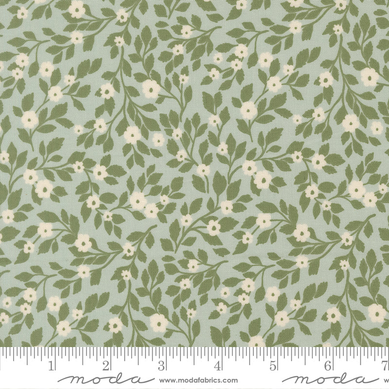 Floral pattern fabric with green leaves and white flowers on a light blue background, featuring a ruler for scale