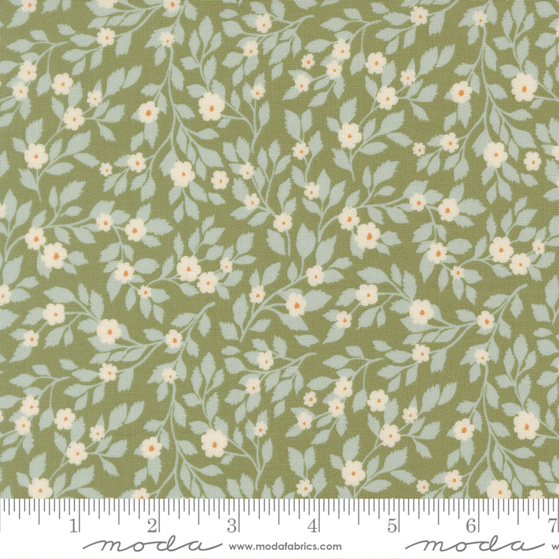 Floral pattern fabric with a ruler at the bottom for scale, featuring light blue leaves and small white flowers on a green background.