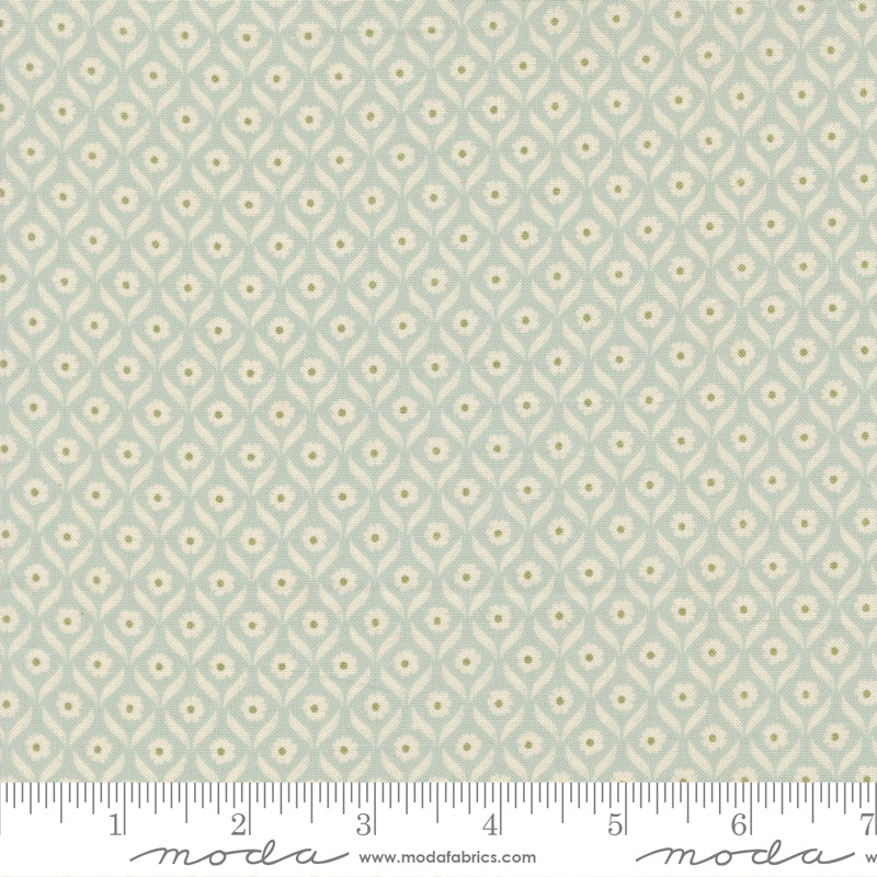 Fabric swatch with a geometric floral pattern on a light blue background, featuring Moda label.