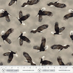 A repeating pattern of bald eagles flying across a warm taupe-gray background, with a Windham Fabrics ruler along the bottom showing the scale of the print.