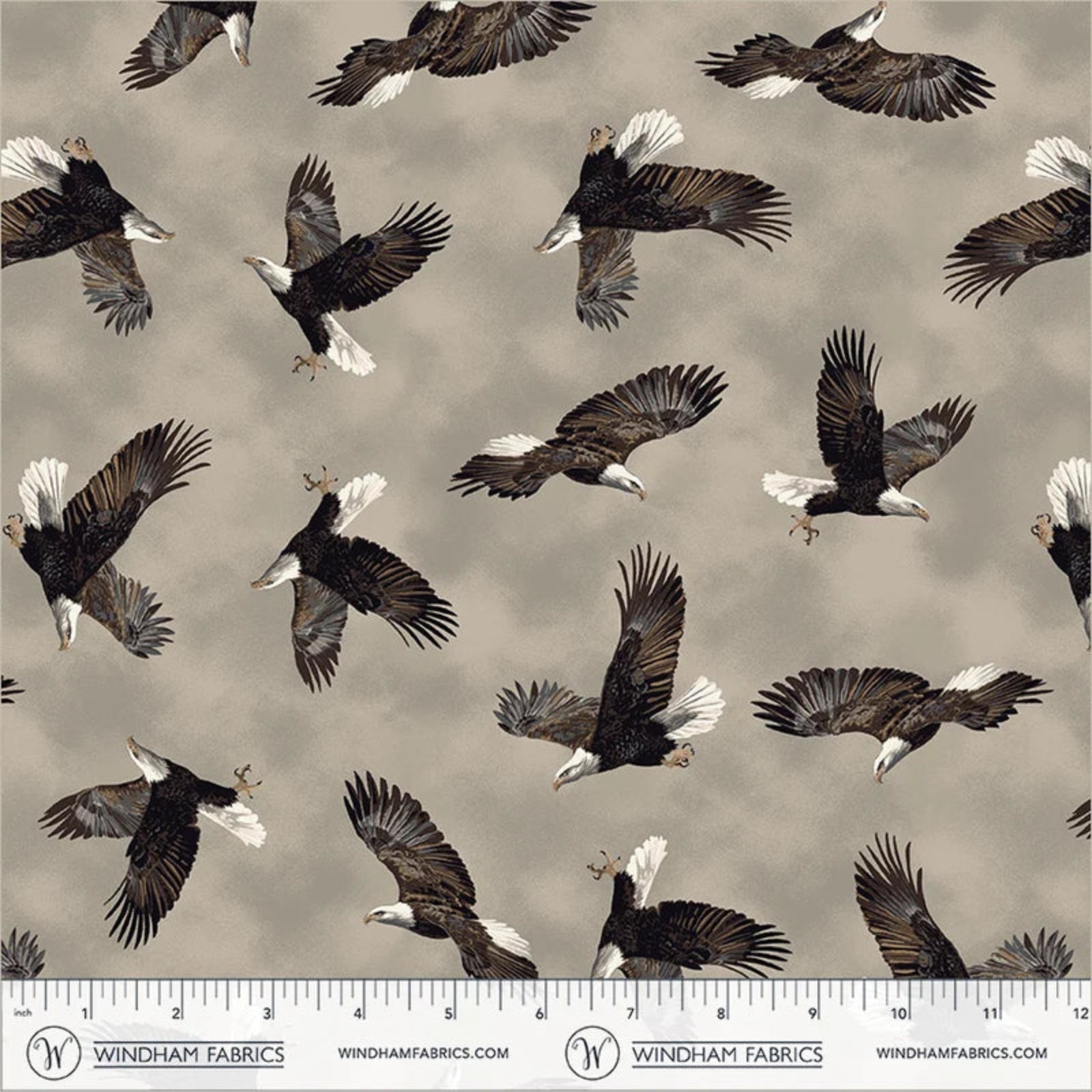 A repeating pattern of bald eagles flying across a warm taupe-gray background, with a Windham Fabrics ruler along the bottom showing the scale of the print.