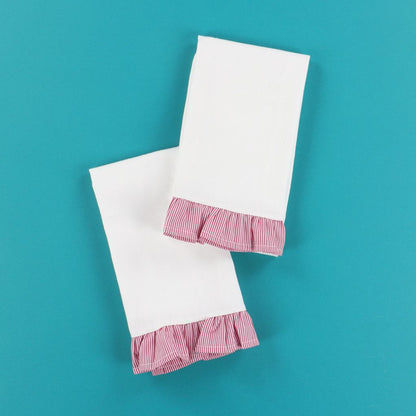 Two white towels with red stripped ruffles on a teal background