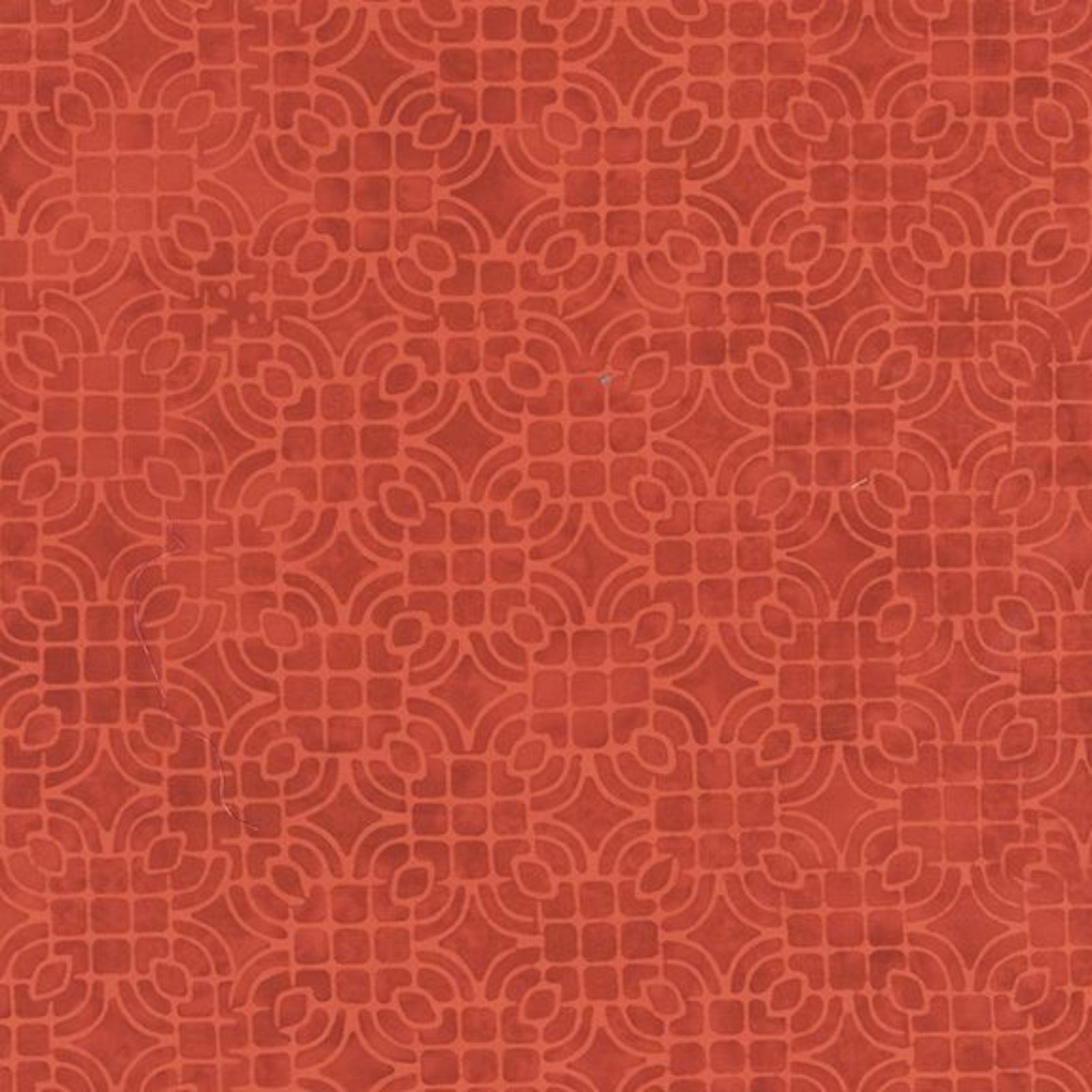 A close-up of a terracotta red fabric or material with a repeating embossed geometric pattern.