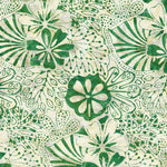 A close-up of a batik fabric pattern featuring green hand-painted style floral and leaf motifs on a warm cream background.