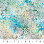 A close-up of a fabric pattern featuring watercolor-style tropical floral motifs in shades of turquoise blue, sage green, and cream, with a white ruler along the bottom edge showing measurements.