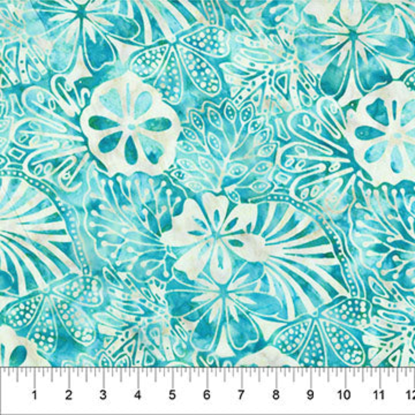 A close-up of a batik fabric pattern featuring teal, turquoise, and off-white tropical floral and leaf motifs, with a white ruler at the bottom showing the scale.