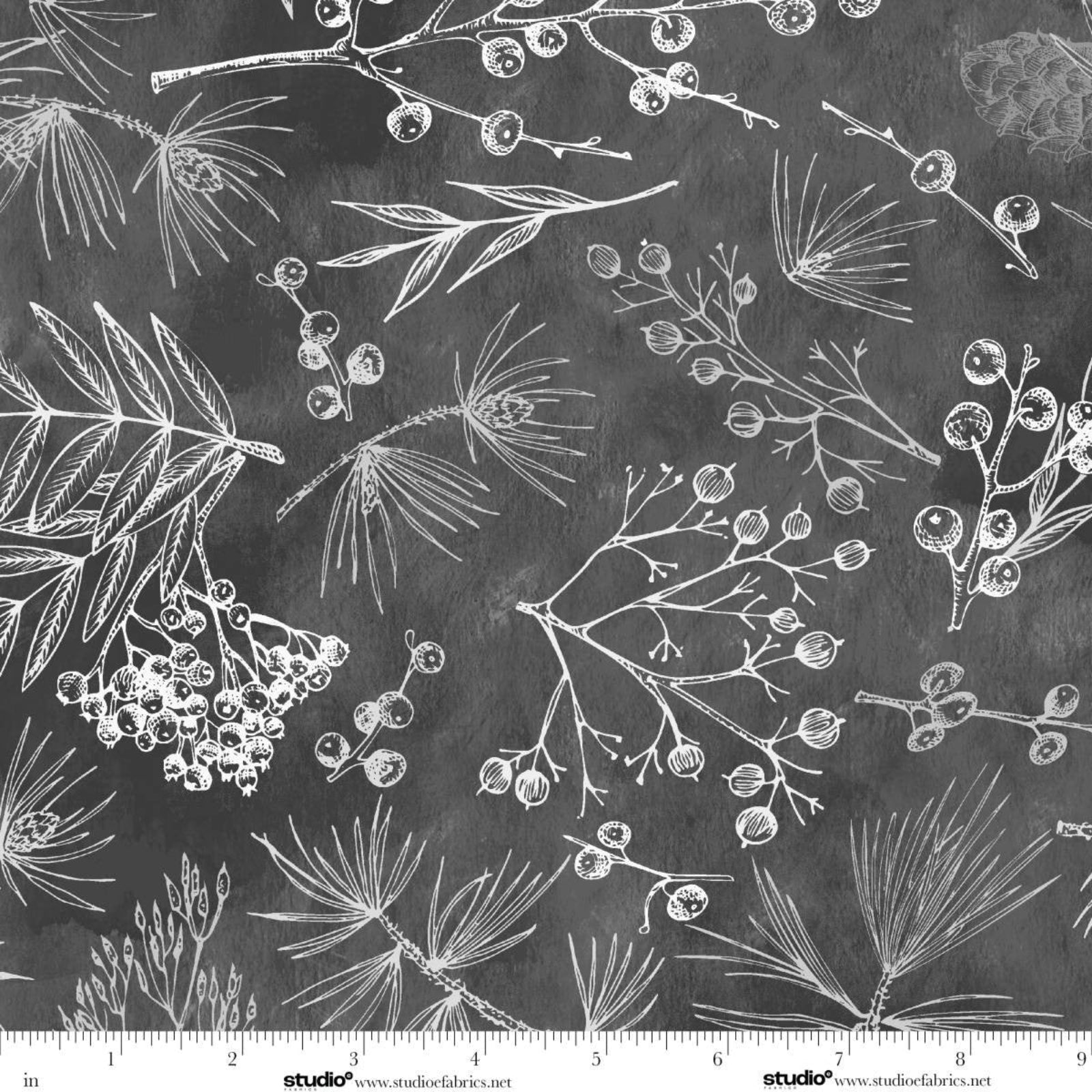 A close-up of a fabric pattern featuring white hand-drawn botanical illustrations of pine branches, leaves, and berry clusters on a dark charcoal gray background. A white measurement ruler is visible along the bottom edge with the brand name Studio Fabrics printed on it.