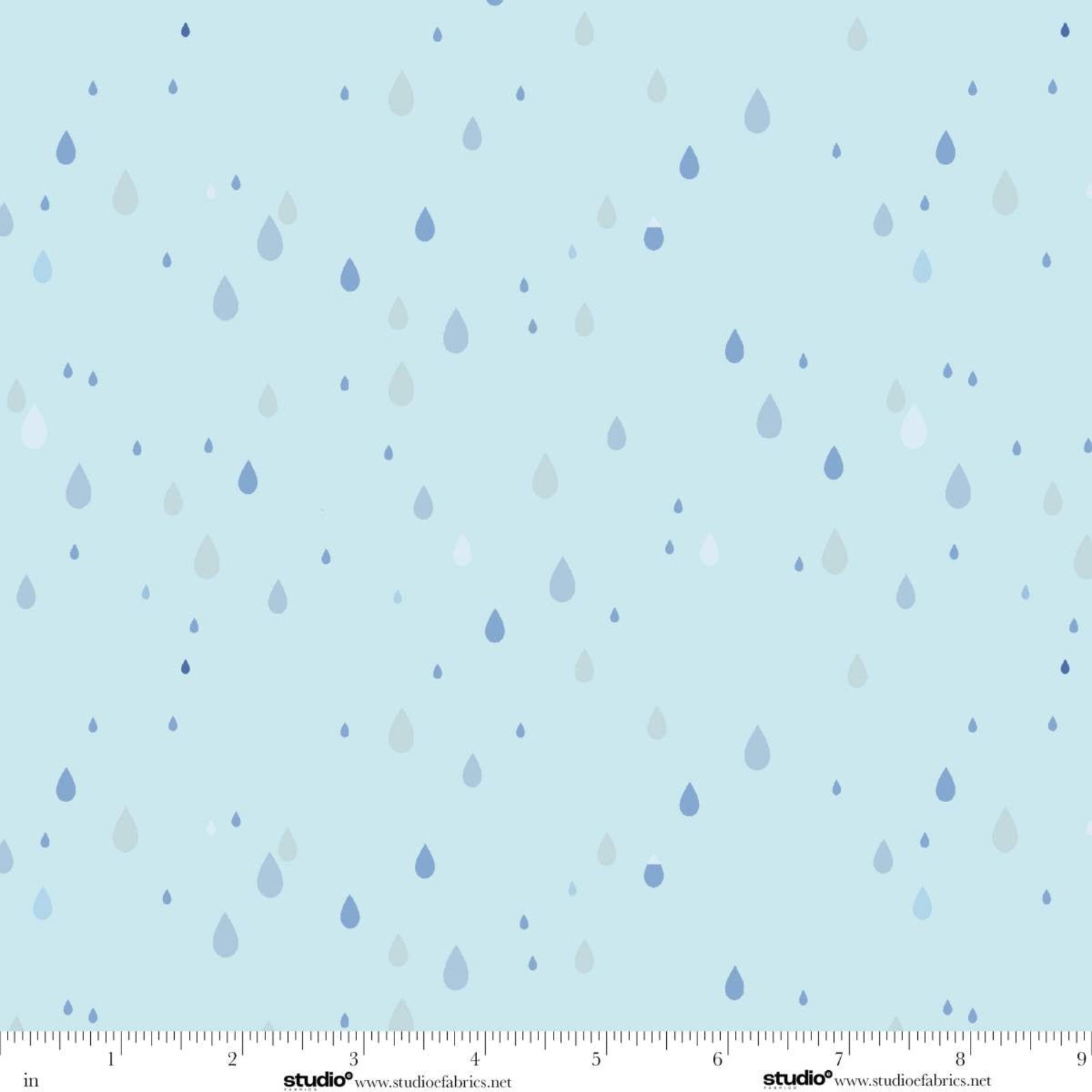 Light blue fabric with a scattered pattern of small raindrops in shades of blue, navy, and white, shown with a measurement ruler along the bottom edge.