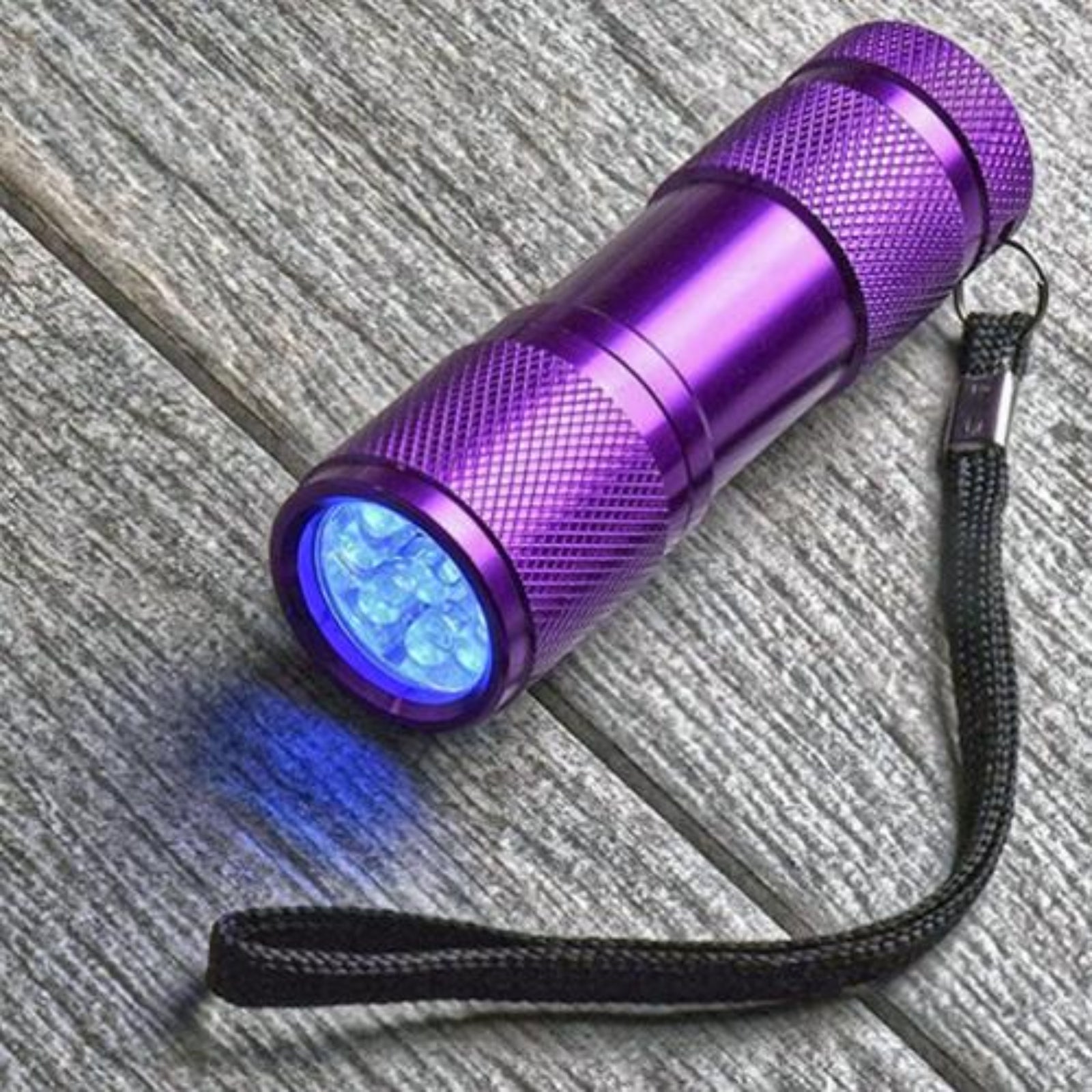 Purple UV flashlight with blue light on a textured surface