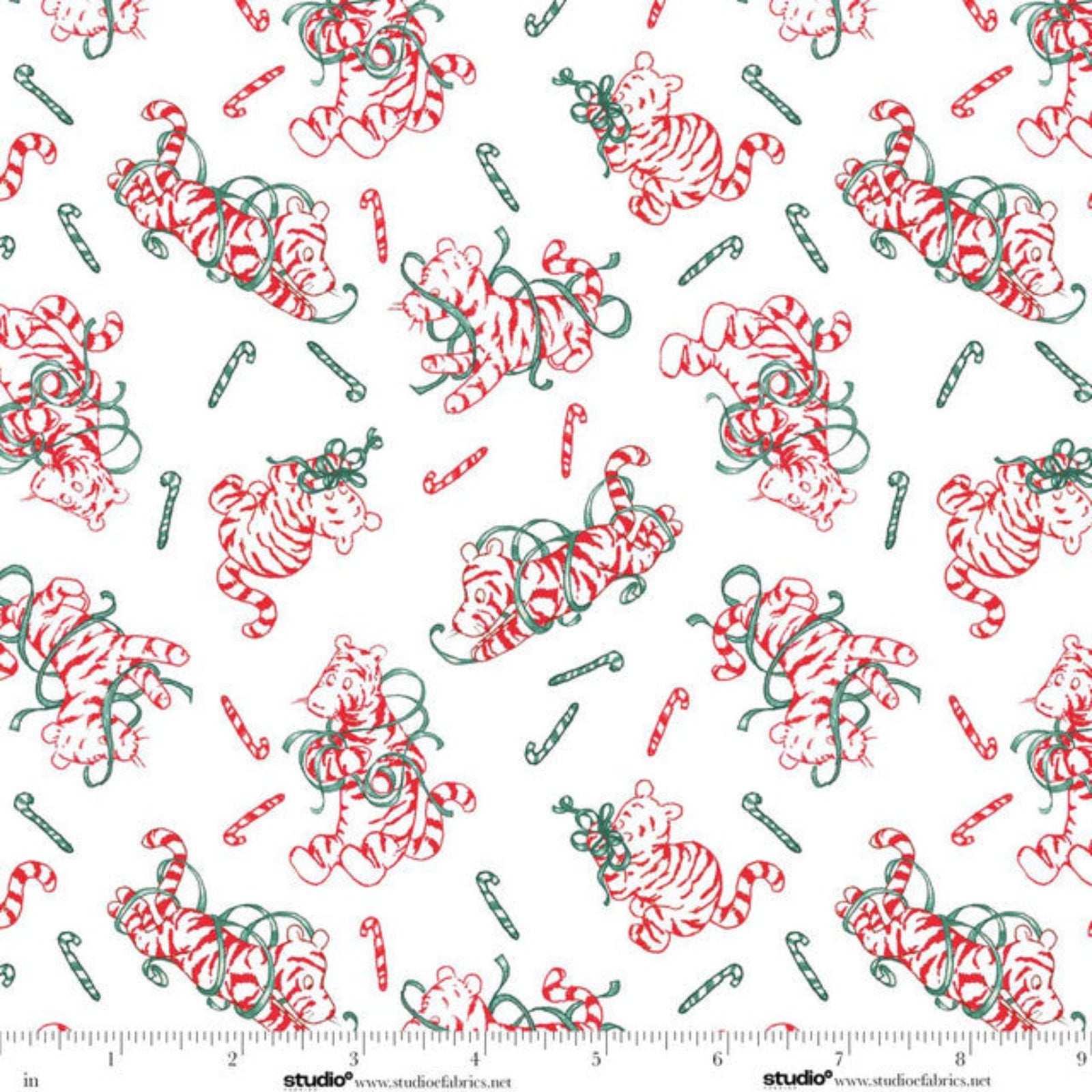 A repeating fabric pattern featuring red and white striped tigers and green candy canes on a white background, with a small Studio E Fabrics ruler visible along the bottom edge.