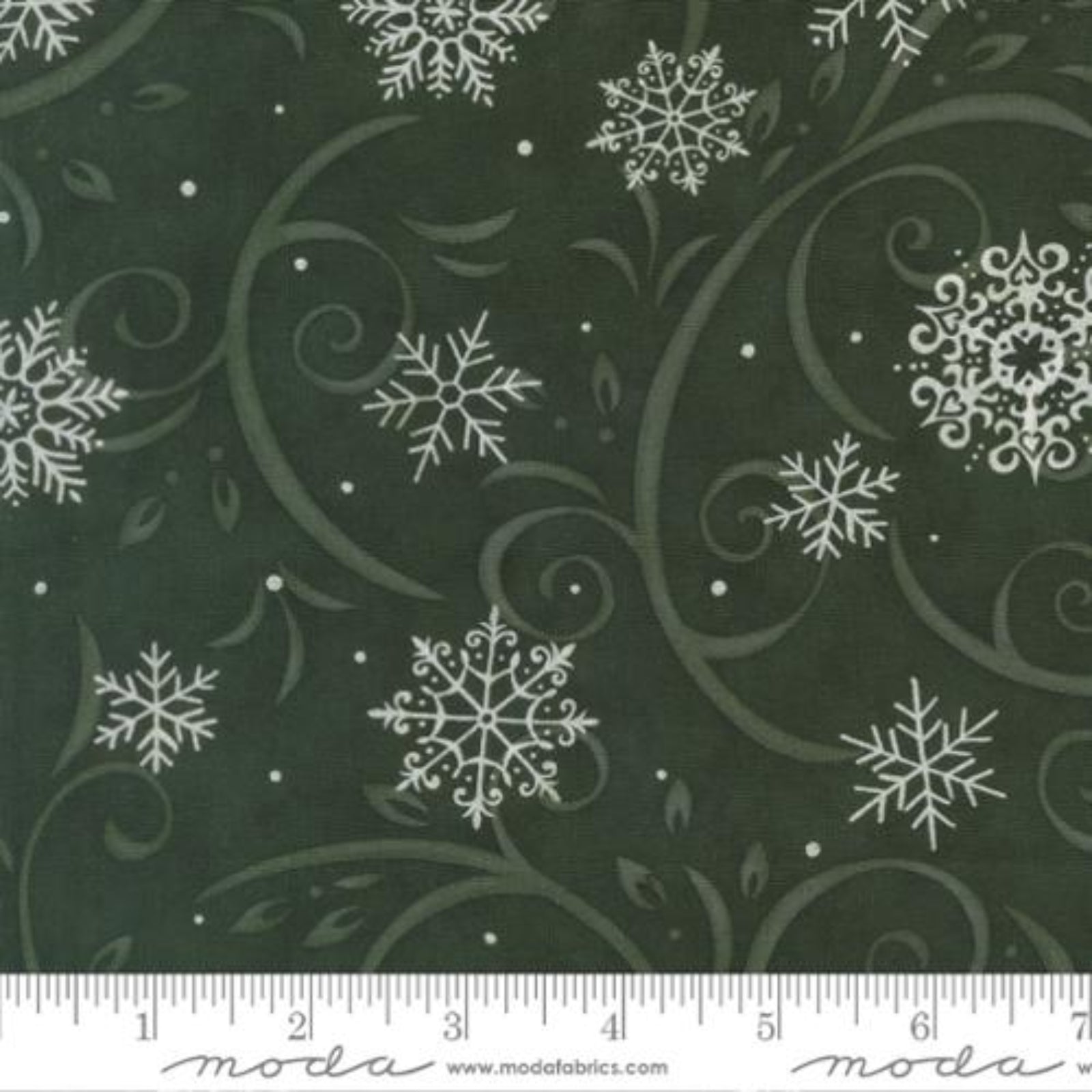 Fabric with white snowflakes and swirls on a green background, featuring Moda label.
