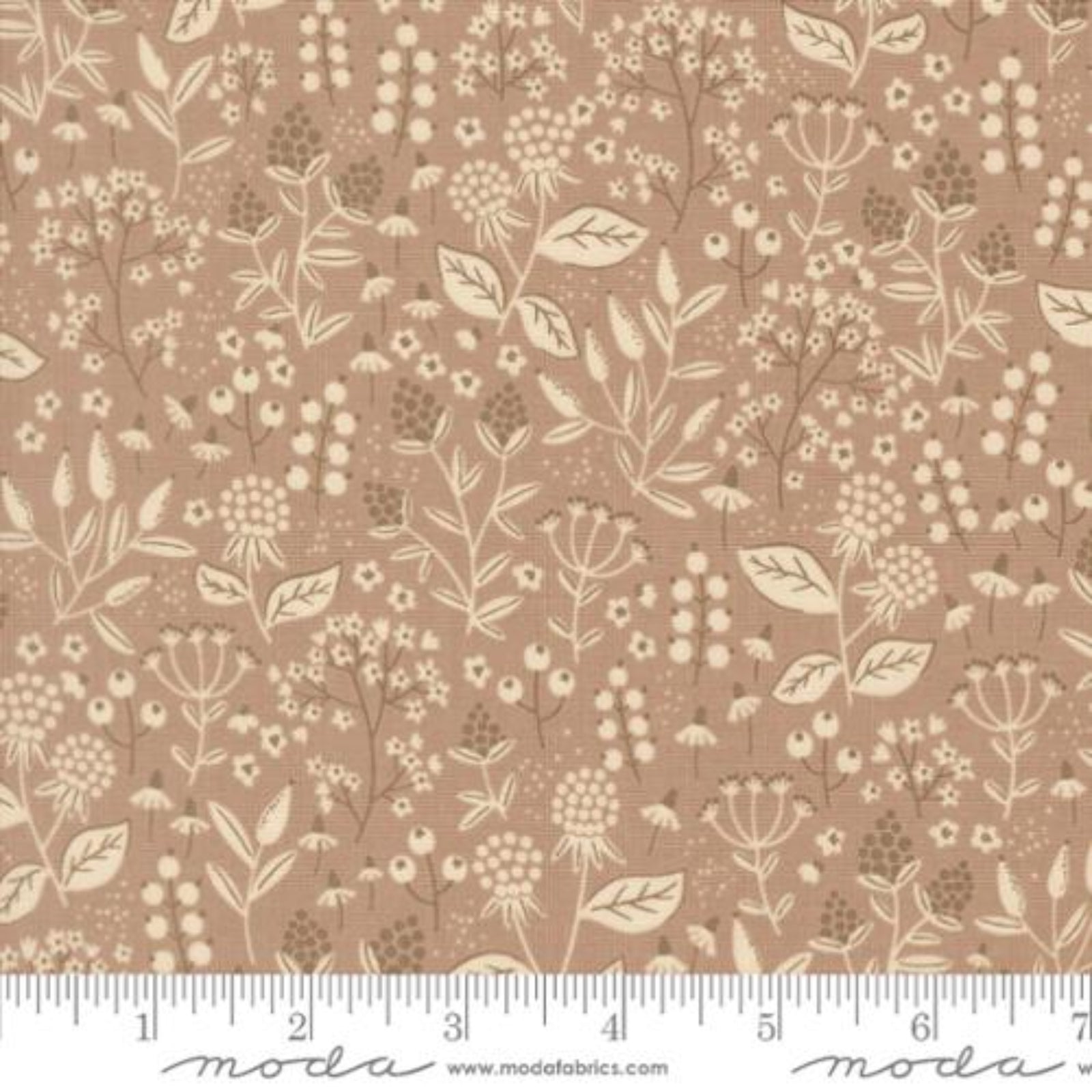 A close-up of a fabric pattern featuring a delicate beige and brown botanical print on a warm tan background, with a white ruler along the bottom edge showing measurement markings and the Modas Fabrics logo.