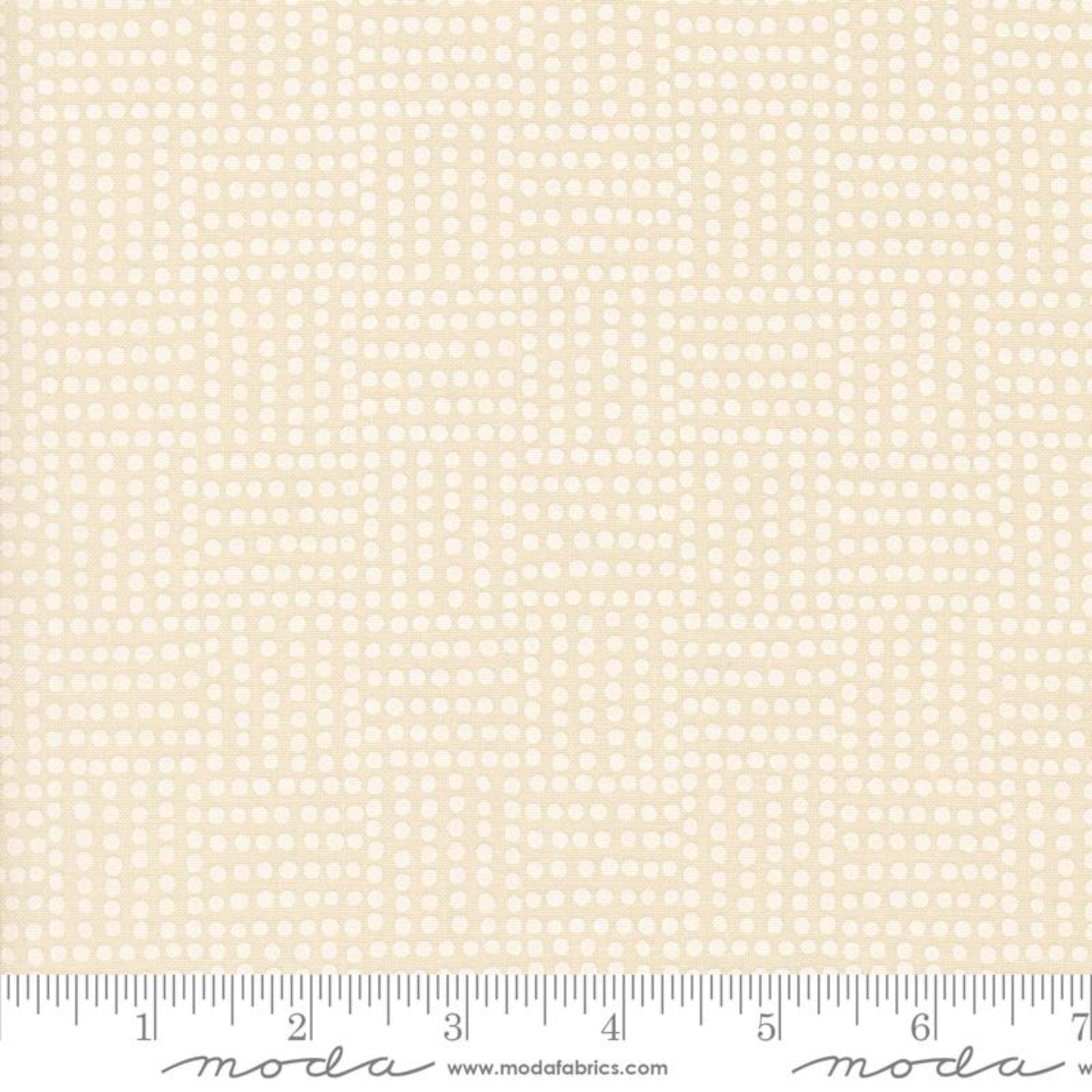 A close-up of a fabric pattern showing a repeating grid of small white circles on a warm cream background, with a ruler along the bottom edge and Modda branding printed at the bottom.