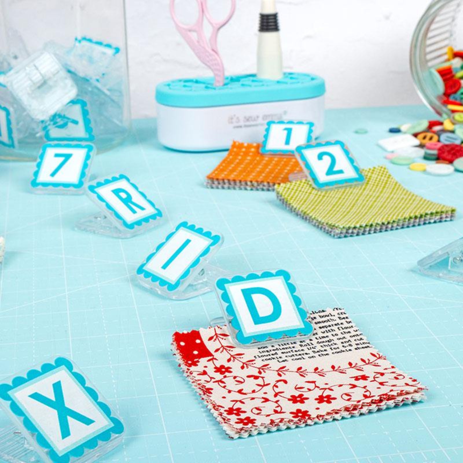 Craft materials with letter tiles and fabric on a blue surface