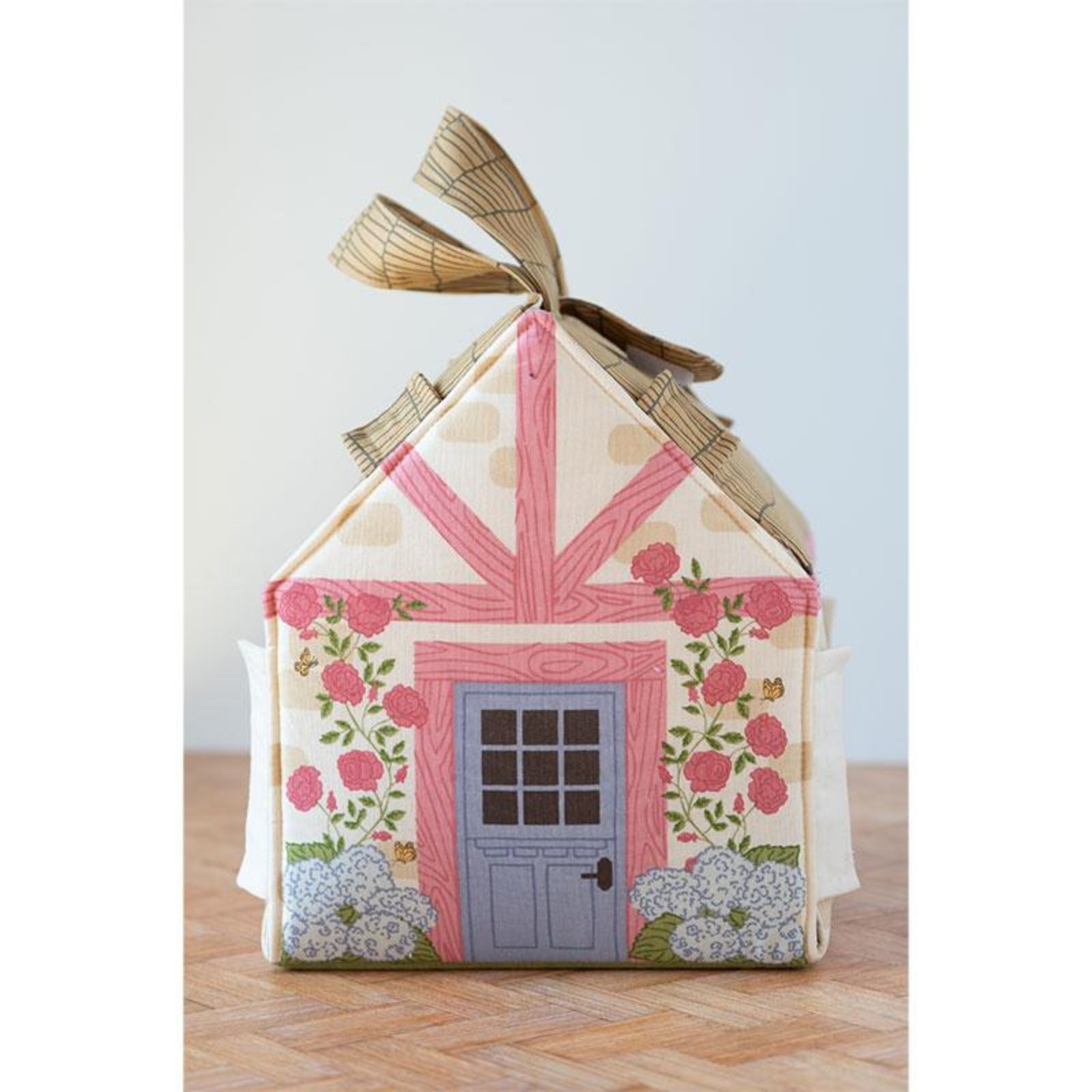 Decorative house-shaped box with floral design and ribbon on a wooden surface